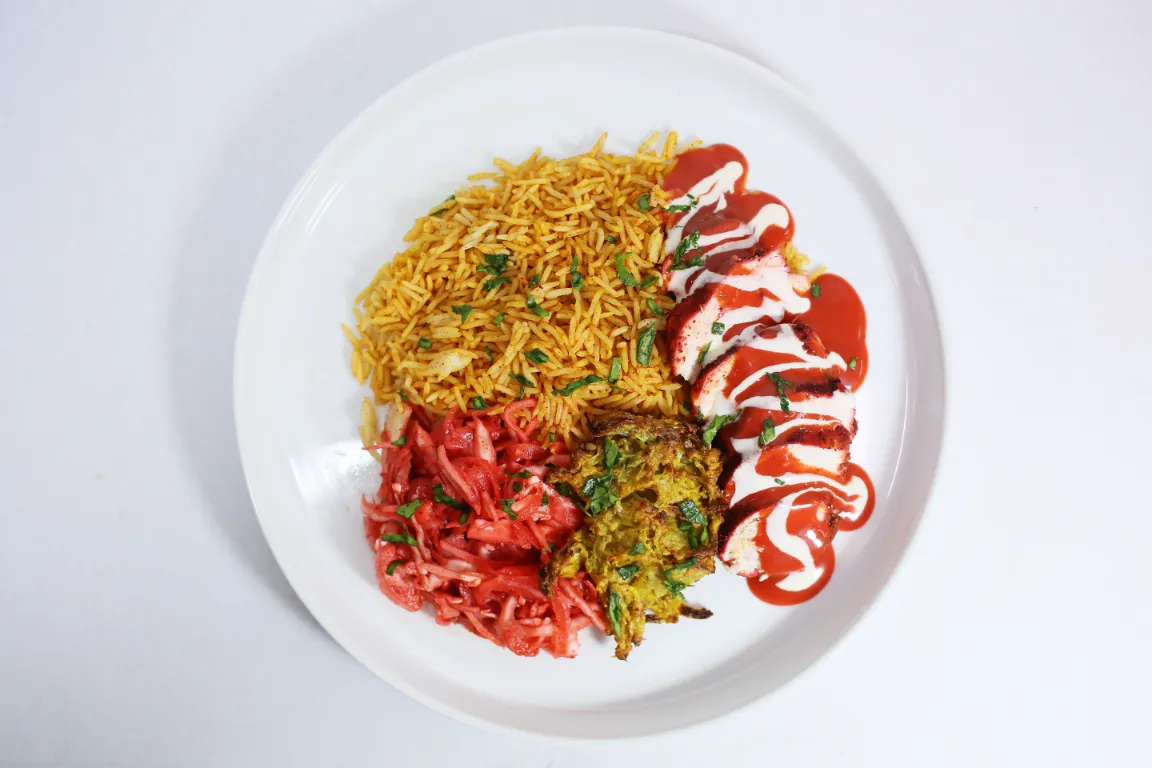 Baba’s Indian Munchie Box, crispy, golden onion bhajis with perfectly seasoned rice, creating a hearty base that’s rich in traditional Indian spices. Topped with fresh Indian slaw for a refreshing crunch, a drizzle of tangy Baba’s sauce, and cooling raita.