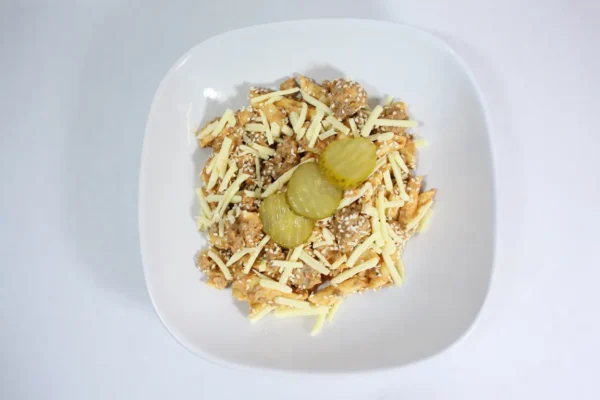 A serving of Cheeseburger Pasta Bake with penne, lean beef, rich cheesy sauce, topped with pickles and sesame seeds, capturing the essence of a classic cheeseburger.