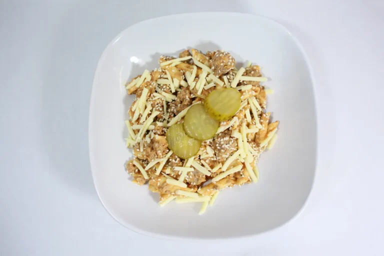 A serving of Cheeseburger Pasta Bake with penne, lean beef, rich cheesy sauce, topped with pickles and sesame seeds, capturing the essence of a classic cheeseburger.