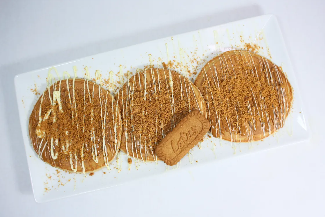 3 fluffy protein pancakes drizzled with white chocolate and biscoff , topped with crushed biscoff cookies