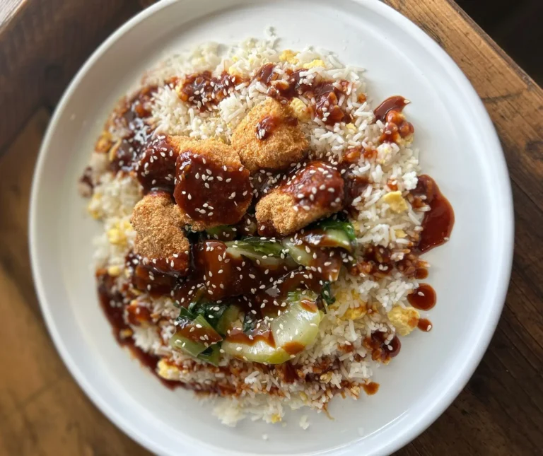 Korean BBQ Crispy Chicken served over egg fried rice with sautéed pak choi and sesame seeds, glazed in sweet and smoky Korean-style BBQ sauce.