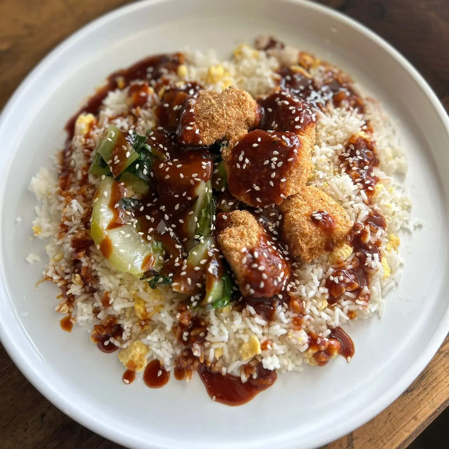 Korean BBQ Crispy Chicken served over egg fried rice with sautéed pak choi and sesame seeds, glazed in sweet and smoky Korean-style BBQ sauce.