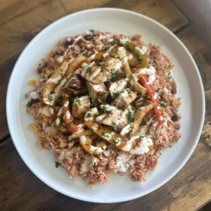 Mexican Fiesta Rice with Chicken featuring grilled chicken breast, spicy rice, black and kidney beans, peppers, onions, and garlic mayo drizzle