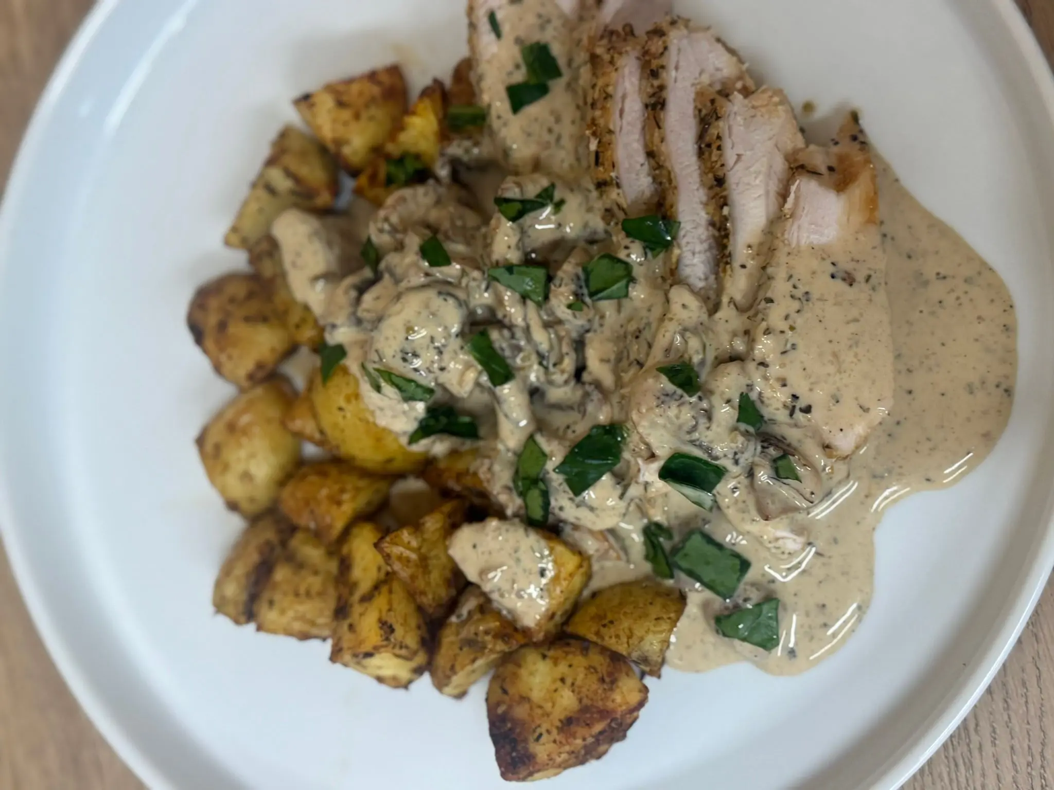 Double Parmesan Chicken with creamy mushroom sauce and roast potatoes on a white plate by Savage Kitchen