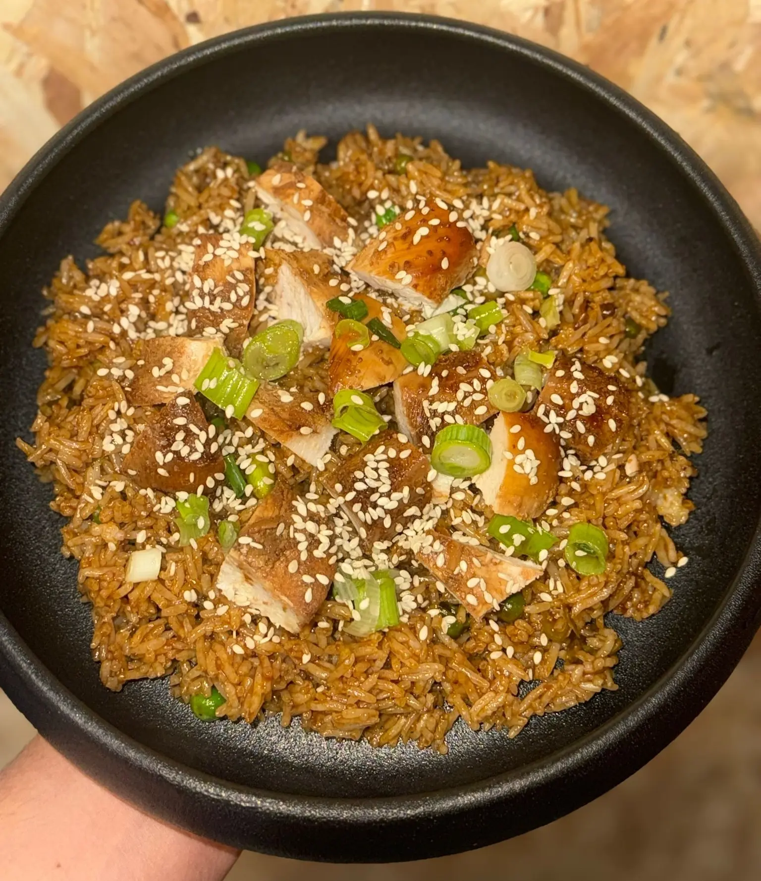 Fragrant Sesame Honey Fried Rice with chicken, edamame, peas, and spring onions. High protein, balanced, and full of sweet-savory flavour, presented on a black plate.