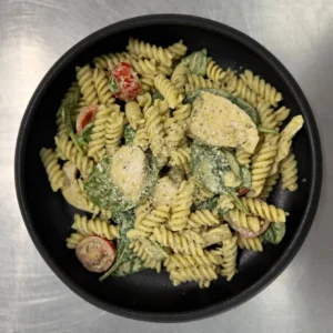 Pesto Pasta with cherry tomatoes, spinach and grated parmesan in a black bowl